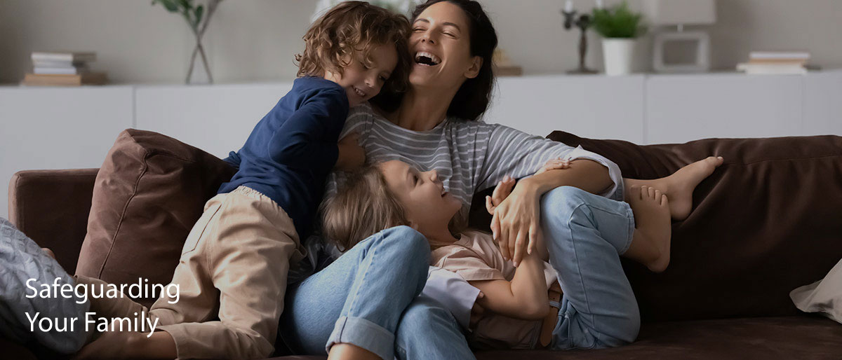 Laughing mom with adorable young kids having fun on comfortable couch at home.