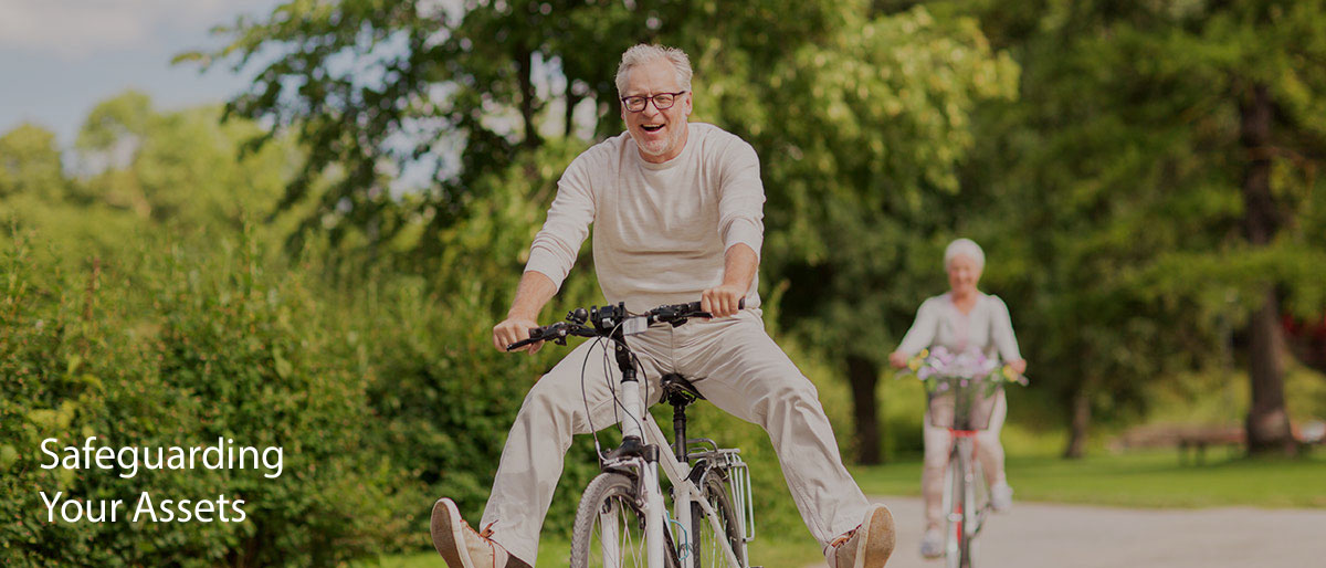 Older couple having fun riding bikes through a sunny park.